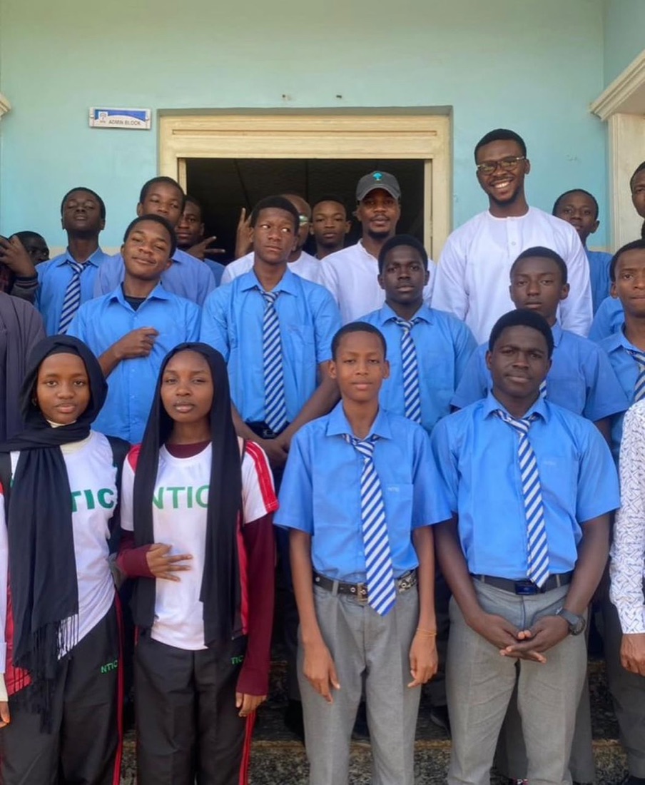 A Teqia team member with secondary school students after an outreach session